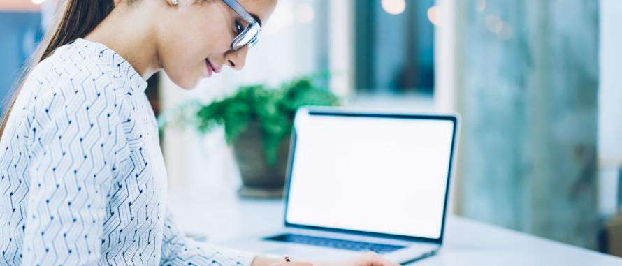 Frau in heller Bluse mit Brille sitzt am Schreibtisch im Hintergrund ein aufgeklappter Laptop, SHBB Bad Oldesloe
