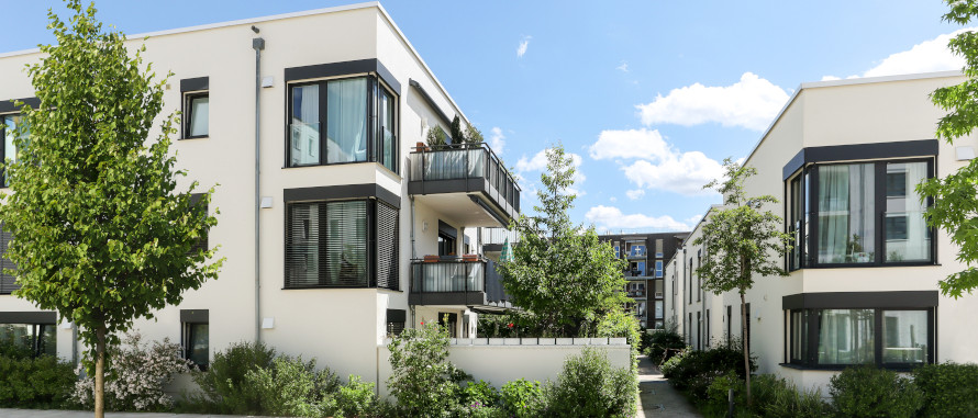 weiß verputzte moderne, dreigeschossige Wohnblöcke eingegrünt